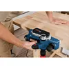 A person is using a blue and black power planer on a wooden surface. Anteprima dell’immagine prodotto