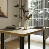 A dining table set for a meal, with a vase of flowers and place settings, in a room with a large window. Produktbild-Vorschau