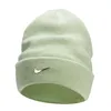 A light green Nike beanie with a silver Nike swoosh logo.