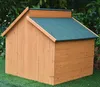 A wooden dog house with a green roof sits on a patch of green grass, with lush green foliage in the background. Voir les images du produit
