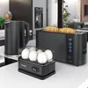 A black electric kettle, a black toaster with toast, and a black egg cooker with eggs are arranged on a white countertop in a modern kitchen setting. Produktbild-Vorschau