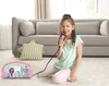 A young girl is sitting on the floor, singing into a pink microphone connected to a pink speaker. A couch and pillows are in the background. Voir les images du produit