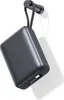 A dark gray power bank is hanging from a hook on a white wall. Produktbild-Vorschau