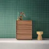 A wooden chest of drawers with decorative items on top, placed next to a striped stool against a green tiled wall. Anteprima dell’immagine prodotto