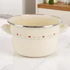 A cream-colored enamel pot with a decorative heart pattern sits on a marble countertop. Produktbild-Vorschau