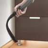 A hand is using a vacuum cleaner hose to clean the corner of a cabinet. Produktbild-Vorschau