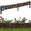 A woven willow garden border with pointed stakes, shown against a white background with a floral and grass foreground. Náhled obrázku produktu