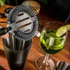 A cocktail shaker and a glass of green liquid with a lemon slice. Voir les images du produit