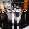 A stainless steel pressure cooker is placed on a black stovetop, with kitchen shelves and jars in the background. Produktbild-Vorschau