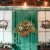 A festive Christmas hanging basket decoration is displayed on a green door, with smaller wreaths on either side and festive greenery below. Anteprima dell’immagine prodotto