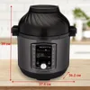 A multi-cooker with an air fryer lid is shown on a wooden surface with kitchen background. Produktbild-Vorschau