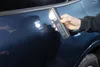 A hand holding a flashlight to inspect a car door. Podgląd zdjęcia produktu