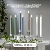 Several LED candles in different colors are displayed on a white surface with greenery around them. Produktbild-Vorschau
