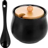 A black ceramic sugar bowl with a wooden lid and a black spoon, presented on a white background. Produktbild-Vorschau
