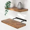 Two wooden shelves mounted on a white wall, one with decorative items and the other showing its mounting bracket. Produktbild-Vorschau