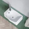 A white ceramic sink with a chrome faucet is mounted on a wall with green tiled backsplash and a wooden floor. Produktbild-Vorschau