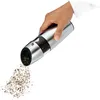 A hand is holding a pepper grinder and grinding pepper onto a white surface. Anteprima dell’immagine prodotto