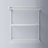 A white, wall-mounted, three-tiered drying rack is shown against a light gray wall. Produktbild-Vorschau