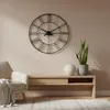 A living room scene with a clock, a chair, and a console table. Voir les images du produit