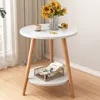 A small round side table with sunflowers and a mug on top, and a basket with magazines on the lower shelf. Produktbild-Vorschau