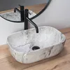A close-up shot of a marble sink with a black faucet. Produktbild-Vorschau