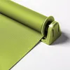 A close-up of a green roller blind attached to a window frame with a clamp mechanism. Produktbild-Vorschau