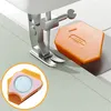 A close-up view of a sewing machine needle and foot, with an orange magnetic seam guide positioned on the fabric. Produktbild-Vorschau