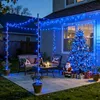 A festive outdoor patio decorated with blue Christmas lights, a Christmas tree, and Santa Claus. Produktbild-Vorschau