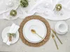 A beautifully set table with white plates, gold cutlery, and a woven placemat, decorated with small wooden hearts and floral accents. Produktbild-Vorschau