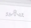 A close-up of a white fabric with a silver crown and floral motif printed on it. Produktbild-Vorschau