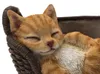 A close-up of a sleeping cat figurine in a basket. Produktbild-Vorschau