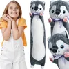 A young girl is posing with a long plush husky toy. Voir les images du produit
