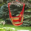 A striped hammock chair hangs from a tree branch in a garden setting. Náhled obrázku produktu
