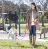 A woman walking a white dog in a park. Anteprima dell’immagine prodotto
