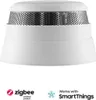 A white smoke detector with a perforated metal top, shown against a white background. Below the product are logos for Zigbee and SmartThings. Náhled obrázku produktu