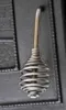 A close-up shot of a metal handle with a coiled spring design, attached to a dark, textured surface, likely a stove or oven door. Produktbild-Vorschau