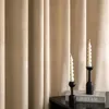 Two white spiral candles in black candle holders are placed on a table in front of beige curtains. Anteprima dell’immagine prodotto