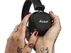 Hands holding black Marshall headphones. Voir les images du produit