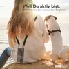 A person and a dog sitting on rocks by the sea, with the sun shining. Produktbild-Vorschau