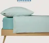 A close-up view of a bed with mint-colored bedding, including a pillow and a fitted sheet. Produktbild-Vorschau