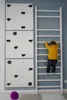 A young child is climbing a white ladder next to a white climbing wall with black grips, in a room with light gray and blue walls. Anteprima dell’immagine prodotto
