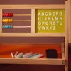A wooden educational toy with an abacus and alphabet board on the top shelf, and chalk and an eraser on the bottom shelf. Produktbild-Vorschau