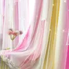 Close-up of pastel pink and yellow gradient curtains with small white stars, layered with sheer white voile curtains. A white vase with fluffy pink and purple flowers sits on a table covered by the curtains. Náhled obrázku produktu