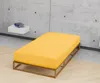 A yellow mattress on a wooden frame in a minimalist room with a concrete wall. Produktbild-Vorschau