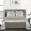Silbernes Seiden-Bettwäscheset auf einem Bett mit vier Kissen und einer Bettdecke, in einem modernen Schlafzimmer Produktbild-Vorschau