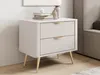 A beige nightstand with gold legs and handles, placed next to a bed. Náhled obrázku produktu