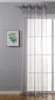 A sheer gray curtain hangs in front of a window with a grid pattern, next to a framed picture of green leaves on a gray wall. Produktbild-Vorschau