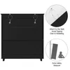 The image shows a black shoe cabinet with safety instructions on the right side. The instructions include diagrams and text about attaching the cabinet to the wall to prevent tipping and wobbling, and an illustration of a child near a tipped-over cabinet a Produktbild-Vorschau
