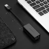 A black Ugreen USB to Ethernet adapter is placed on a black surface next to a laptop keyboard. Voir les images du produit