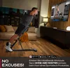 A man is exercising on a fitness bench in a living room setting, with a TV screen showing a workout video. Produktbild-Vorschau